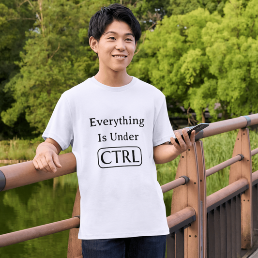 Person wearing a white t-shirt with text standing on a wooden bridge with greenery in the background