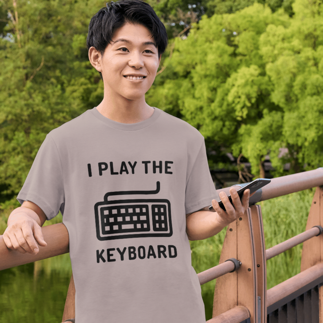 Person wearing a t-shirt with 'I Play the Keyboard' design outdoors.