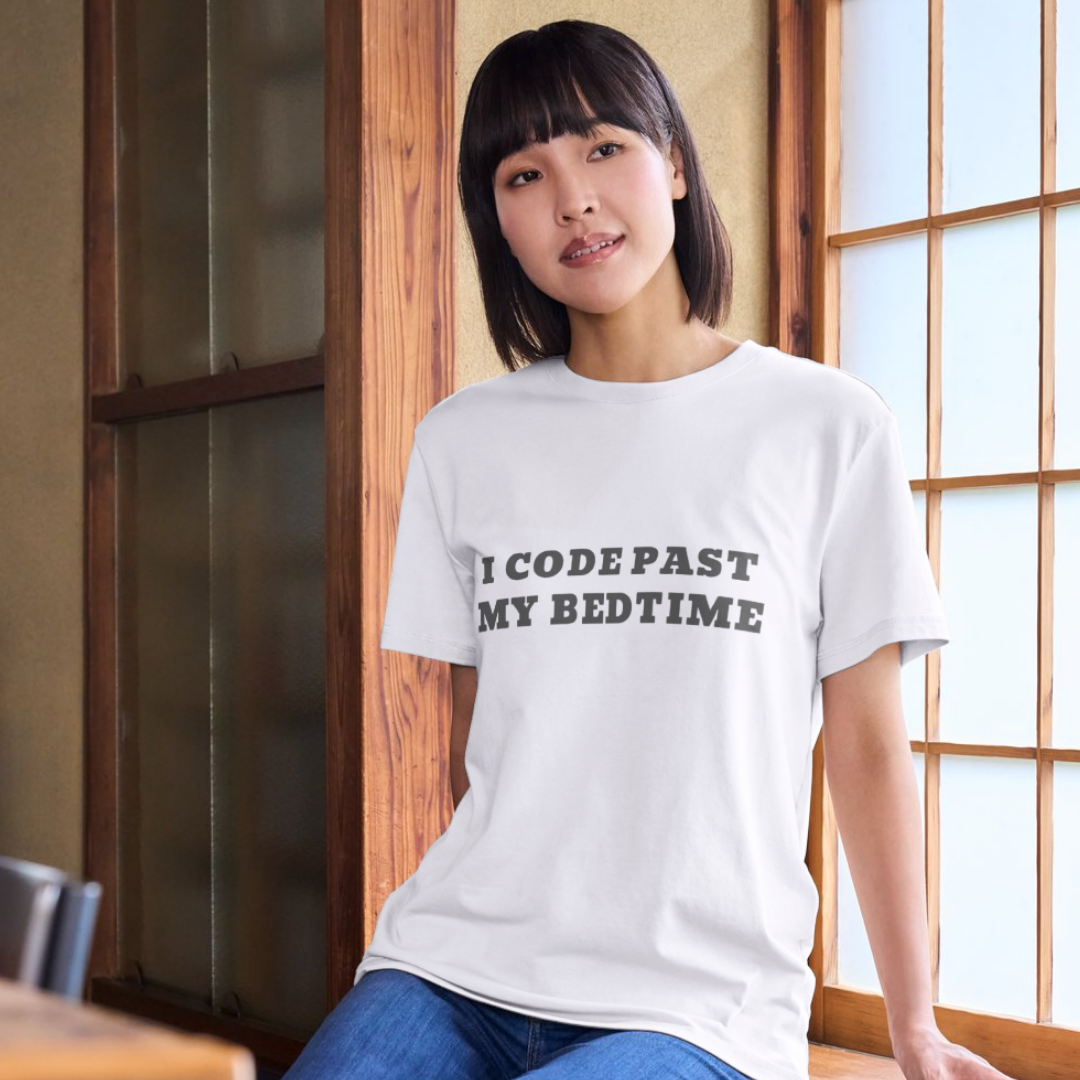 Person wearing a white t-shirt with text in a room with wooden walls and a window.