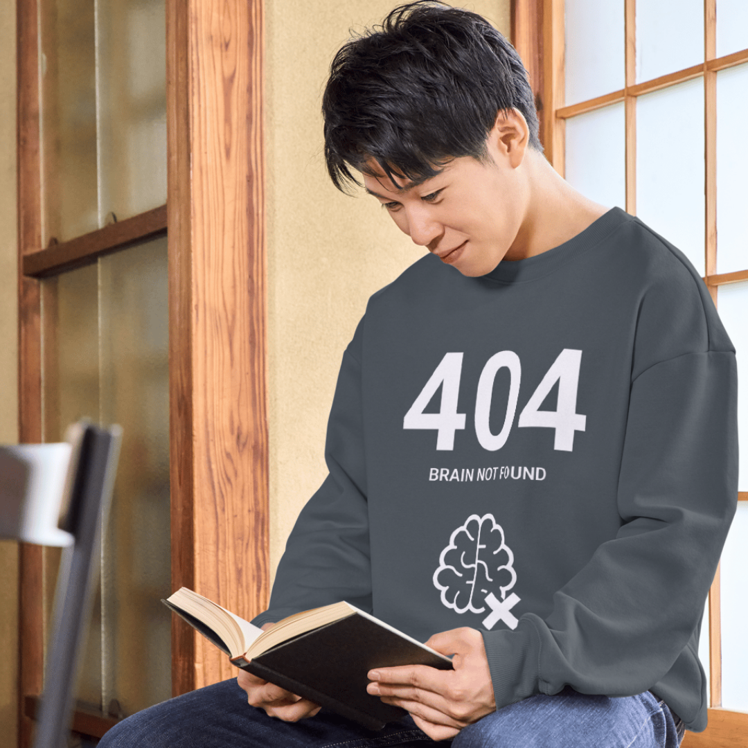Person wearing a dark gray shirt with '404 Brain Not Found' design, holding an open book.