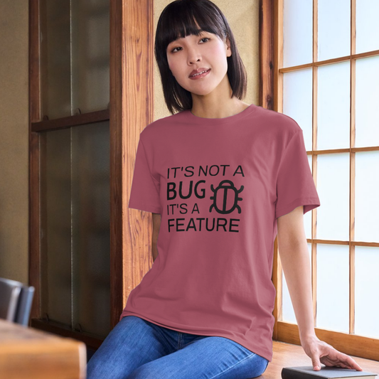 Person wearing a t-shirt with 'It's not a bug, it's a feature' text in a room.