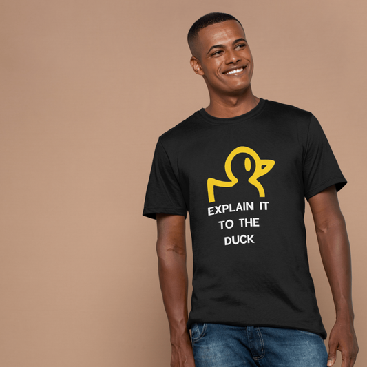 Man wearing a black t-shirt with a yellow duck graphic and text on a beige background