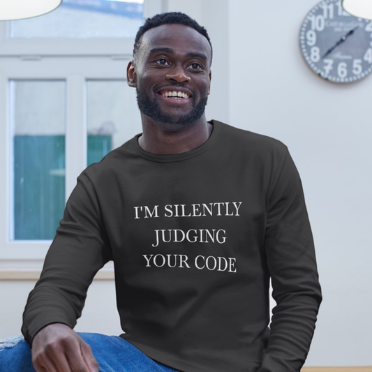 Man wearing a black shirt with coding joke, sitting indoors.