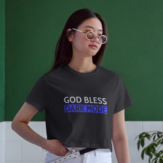 Person wearing a black t-shirt with 'GOD BLESS DARK MODE' text against a green wall.