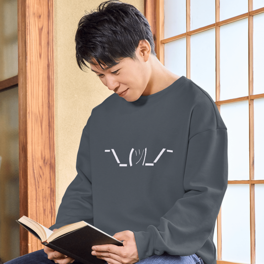 Person wearing a dark gray shirt with a logo, reading a book indoors.