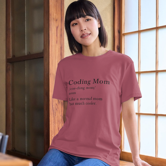 Woman wearing a t-shirt with 'Coding Mom' text in a room with wooden walls and a window.