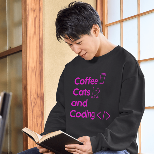 Person wearing a black shirt with 'Coffee, Cats, and Coding' text, holding a book.