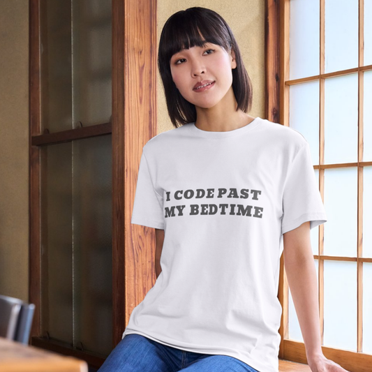 Person wearing a white t-shirt with text in a room with wooden walls and a window.
