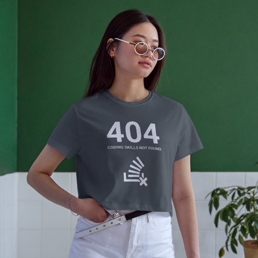 Person wearing a gray t-shirt with '404 Coding Skills Not Found' design against a green wall.